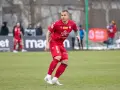Piłkarz Alan Uryga w czerwonej koszulce z numerem 6, na boisku. Miejmy nadzieję, że jego kontuzja nie jest poważna.