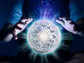 Dłonie unoszą księżyc z tarczą zodiaku, gdzie znaki zodiaku i żywioły splatają się w mistycznym świetle.