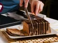 Cortando una porción de la deliciosa tarta de queso casera de la abuela, cubierta con chocolate.