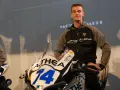 Piotr Biesiekirski, młody kierowca wyścigowy, pozuje obok swojego motocykla z numerem 14.