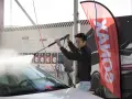 Man tvättar en bil med högtryckstvätt. Vatten sprutar över vindrutan. En röd flagga med texten "MAX" syns i bakgrunden, bredvid en bild av en sportbil. Målet är att polera matt lack.