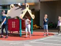 Une animatrice, masque et gants, surveille des enfants sur un terrain de jeu. Le directeur ACM veille à la sécurité.