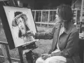 Artystka tworzy portret węglem. Jej ręka z pędzlem zbliża się do płótna, gdzie widoczna jest plama rysunek.