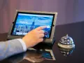 Dłoń dotyka ekranu tabletu z napisem "Welcome to UpScale". Czy osoba niepełnoletnia może zameldować się w hotelu? Obok dzwonek hotelowy.
