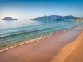 Spokojna plaża Caretta z łagodnymi falami i wyspami w oddali. Idealne miejsce na relaks.