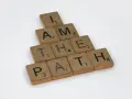 Bokstäver på träbrickor bildar frasen "I AM THE PATH" i en bunden form.