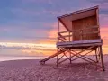 Drewniana wieża ratownicza na plaży o zachodzie słońca. Piasek i ocean tworzą tło dla tego malowniczego krajobrazu, który może być właśnie w Urugwaju, gdzie leży ten piękny kraj.