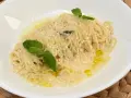 Spaghetti al limone cremosi, cosparsi di parmigiano e guarniti con foglie di menta fresca. Un piatto profumato e invitante.