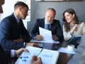 Team discusses broker-dealer compliance, reviewing charts and documents in a meeting.