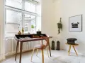 Ett elegant skrivbord i oljad ek med en läderklädd stol. En gammal skrivmaskin står på ett litet sidobord.