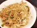 Pyszny pad thai oryginalny przepis z kurczakiem, kiełkami i orzeszkami ziemnymi na białym talerzu.