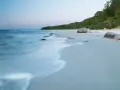 Spokojne plaże nad Bałtykiem o świcie, z delikatnymi falami i kamieniami na piasku.