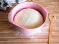 Ein aufgegangener Teig in einer rosa Schüssel, bereit zum Backen. Daneben liegt ein Holzlöffel mit Herz. Was ist Germ?