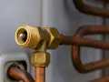 Mosiężny zawór schrader z miedzianymi rurkami, element układu klimatyzacji.