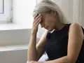 Kobieta z ręką na czole, cierpiąca na zawroty głowy związane z menopauzą.