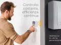 Uomo interagisce con il termostato per un controllo costante e un'efficienza continua. L'interfaccia di ultima generazione garantisce comfort e risparmio.