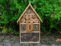Casetta per insetti fai da te, un rifugio accogliente con legni forati, bambù e pigne, pronto ad ospitare piccoli amici del giardino.