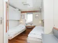 Przytulna stena spirit kabiny z dwoma łóżkami, oknem i szafkami.