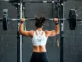 Femme musclée soulevant une barre chargée, prête pour un superset musculation intense.