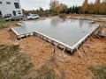 Świeżo wylany beton na budowie. To solidne, najtańsze fundamenty pod przyszły dom, otoczone drewnianym szalunkiem.