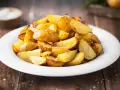 Patate al forno con buccia, dorate e croccanti, servite su un piatto bianco. Un contorno semplice e gustoso.