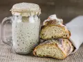 Ein Glas Sauerteig und zwei frisch gebackene Brotscheiben. So ist Sauerteig als Brot ein Genuss.