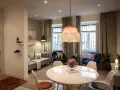 Una sala da pranzo moderna con tavolo bianco, sedie, divano, poltrone blu e un globo decorativo.