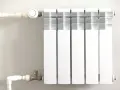 Biały grzejnik z termostatem, podłączony do instalacji rurowej. To efektywne ogrzewanie etażowe, które zapewnia komfort cieplny.