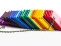 A rainbow fan of acrylic sheets, showcasing varying shades and the material's density, is held together by a silver chain.