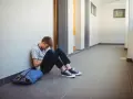 Chłopiec siedzi na korytarzu, przygnębiony. Może potrzebuje pomocy kuratorium?