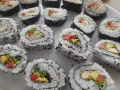 Pyszne domowe sushi z kurczakiem, awokado i warzywami, posypane czarnym sezamem.
