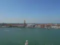 Venezia dall'alto, con il Campanile di San Marco che svetta tra i tetti rossi e il Canal Grande animato da vaporetti e barche.