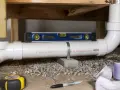 Niveau à bulle sur un tuyau de PVC pour l'évacuation WC. Un mètre ruban et un marqueur sont visibles au premier plan.