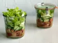 Frischer Salat im Glas, perfekt für eine Party. Schichten aus knackigem Salat, Gurken und Tomaten mit Dressing.
