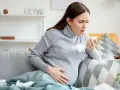 Kobieta w ciąży kaszle, trzymając chusteczkę. Szuka informacji, co na kaszel w ciąży, by ulżyć sobie i dziecku.
