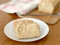 Skivor av hembakat bröd på en vit tallrik, perfekt för snabb bakning. En bit bröd ligger på en skärbräda i bakgrunden.