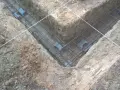 Zbrojenie fundamentów prefabrykowanych w wykopie. Stalowe pręty tworzą siatkę, gotową do zalania betonem.