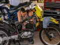 Mężczyzna majstruje przy żółtym motocyklu Suzuki. Rozrusznik kręci, a motocykl nie odpala.