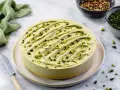 Cheesecake al pistacchio cremosa, decorata con granella verde brillante. Un dolce invitante pronto per essere gustato.