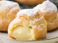 Trois choux à la crème généreusement garnis de crème pâtissière à la vanille, saupoudrés de sucre glace.