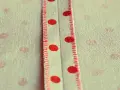 Tessuto a pois rossi con cucitura a punto sopraggitto a mano che crea un dettaglio decorativo.
