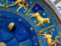 Złoty koziorożec na niebieskiej tarczy zegara astronomicznego, otoczony gwiazdami i cyframi. Dlaczego koziorożec milczy? Może czeka na swój czas.