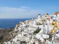 Malownicze białe domy Santorini wznoszą się na klifie nad błękitnym morzem. Wiatraki i kopuły kościołów dodają uroku. Idealne miejsce na rejs promem z Krety.