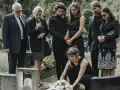 Famiglia in lutto, vestiti di nero, si riunisce al cimitero. Un esempio di come vestirsi a un funerale, con abiti sobri e rispettosi.