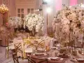 Eleganckie stoły z białymi kwiatami i złotymi krzesłami tworzą styl glamour wesele.