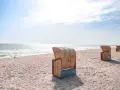 Strandkörbe am Dahme Strand unter blauem Himmel. Das Meer glitzert in der Sonne.