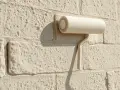 Rouleau à peinture sur un mur en parpaing texturé de couleur crème.