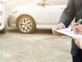 Ubezpieczyciel spisuje protokół szkody, zapewniając ochronę zniżek OC po kolizji dwóch samochodów.