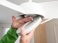 Man installing a ceiling fan with light. Close-up of hands connecting wires to the light fixture.