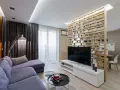 Acogedor salón de 18 metros cuadrados con sofá morado, lámpara de pie y separador de ambiente de madera.